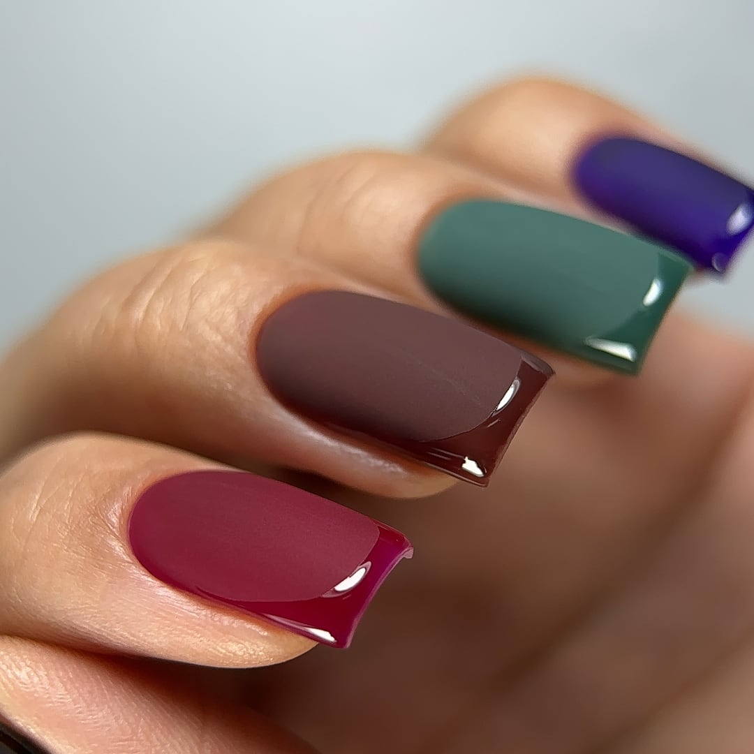 Close-up of a French manicure featuring burgundy, brown, green, and purple gel polish by Paloma from Mystery Forest Collection, with a matte top coat and glossy top coat. Showcasing Paloma's professional gel polish in bold colors, this manicure highlights the contrast between a matte finish and a glossy tip for a sophisticated, textured look ideal for gel nail art.