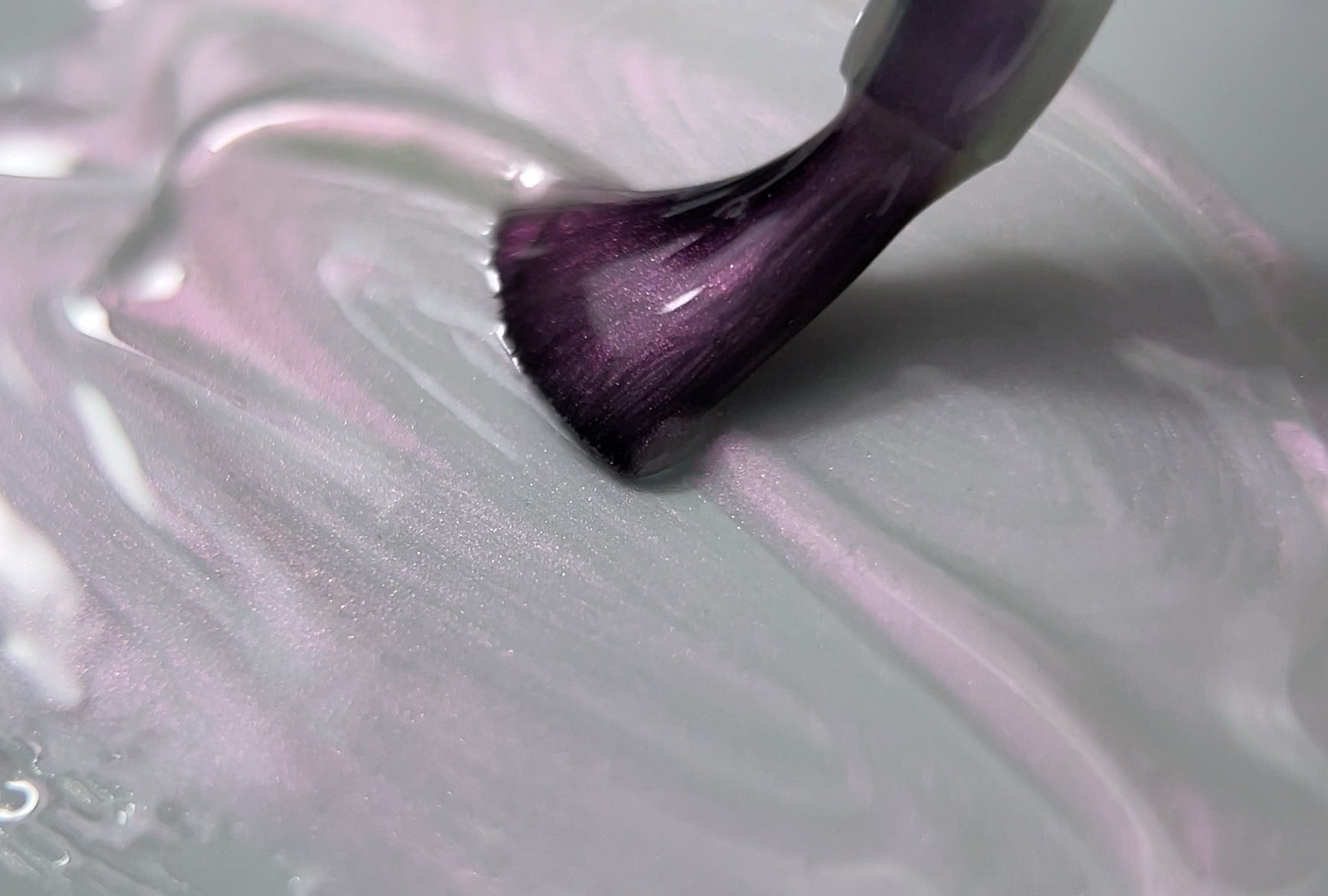 Close-up of a nail brush applying Paloma Magic Top pink gel top coat with a shimmering finish, creating a smooth, glossy texture for a professional gel manicure. Ideal for adding a radiant shine to nail art and enhancing the durability of gel nails.